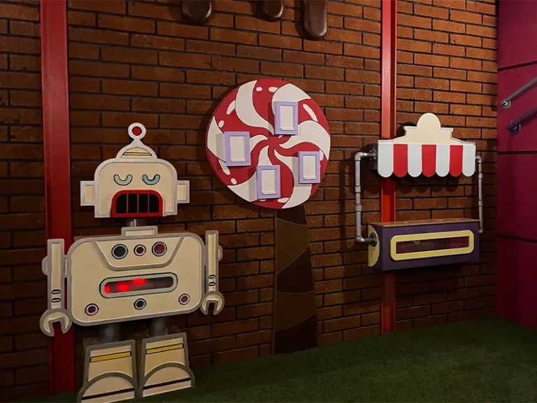 Ein bunter Roboter steht vor einer Zuckerstangen-Dekoration und einem Verkaufsstand in einer fantasievollen Umgebung.