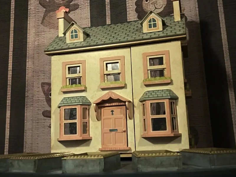 Detailreiche Miniatur eines gelben Hauses mit grünem Dach und Fensterläden, ideal für Sammler und Enthusiasten.
