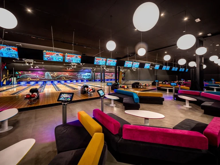 Moderne Bowlingbahn mit gemütlichen Sitzbereichen und bunten Sofas, ideal für Freizeitaktivitäten und Gruppen.