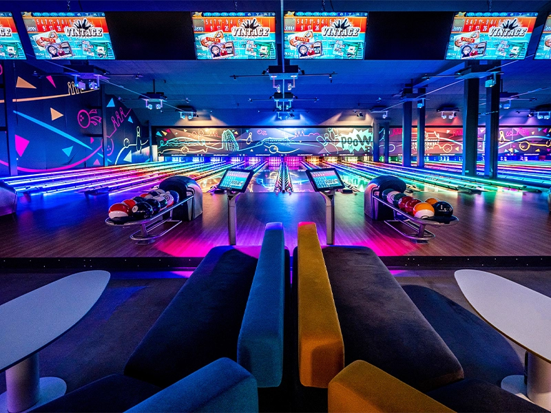 Bunte Bowlingbahn mit moderner Beleuchtung und komfortablen Sitzgelegenheiten für ein unterhaltsames Erlebnis.