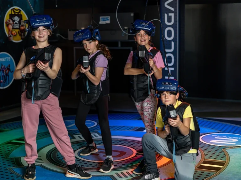 Kinder in VR-Ausrüstung posieren in einem modernen Virtual-Reality-Spielbereich. Spaß und Abenteuer erleben.