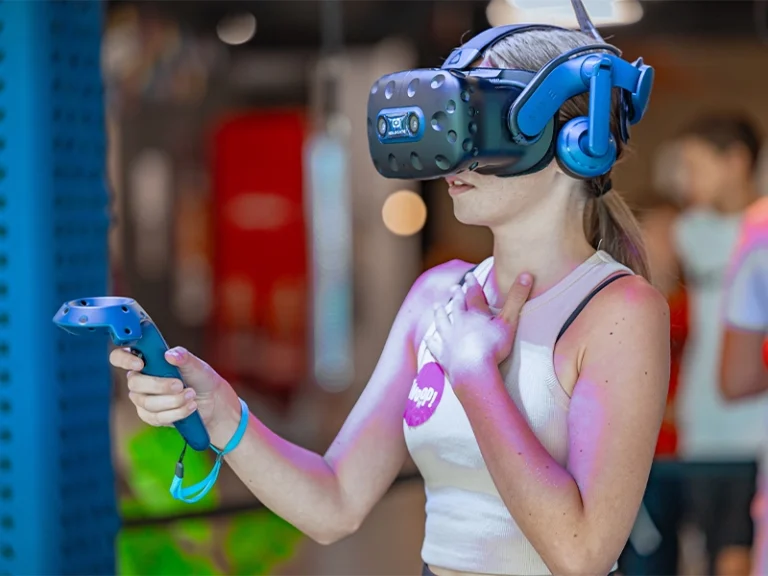 Junge Frau mit VR-Headset erlebt ein immersives Virtual-Reality-Spiel in einer modernen Spieleumgebung.