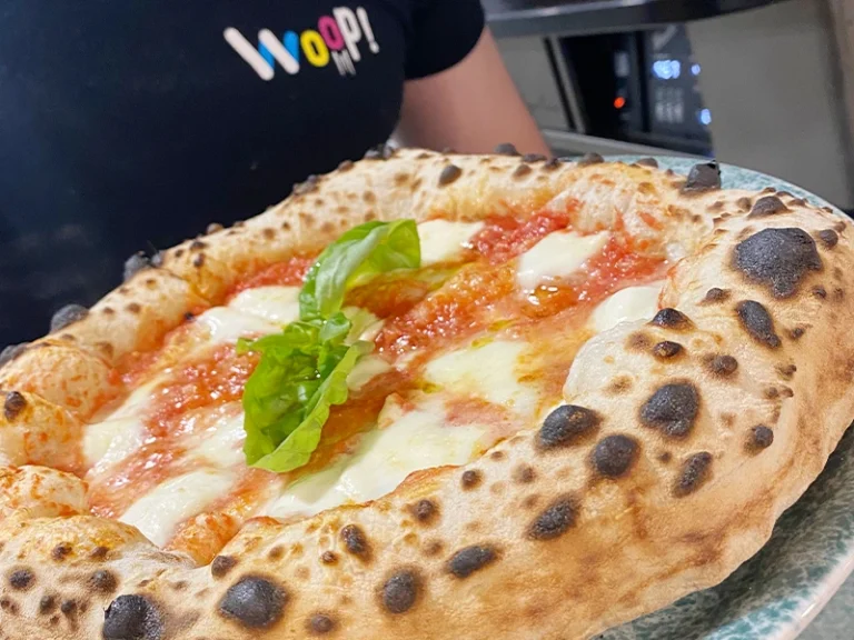 Frische Pizza mit Mozzarella und Basilikum, serviert in einer Pizzeria. Perfekt gebacken mit knusprigem Rand.