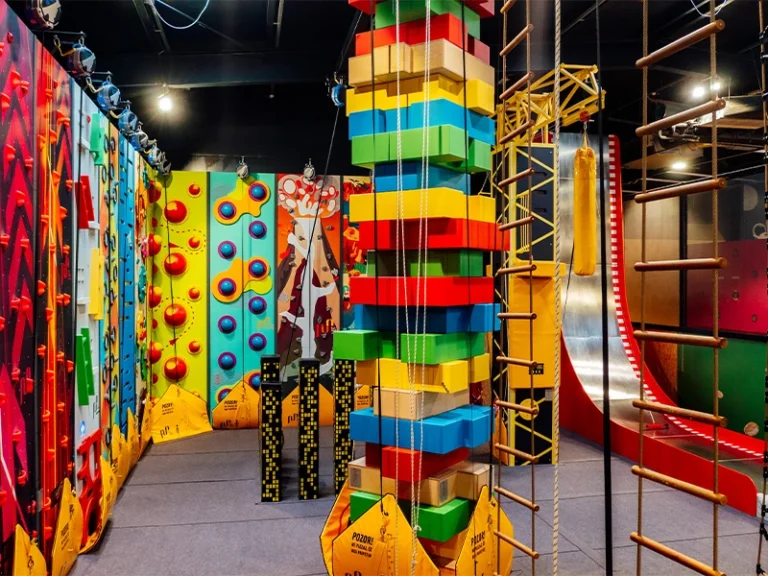 Bunte Kletterwand und Spielgeräte in einem Indoor-Spielplatz, ideal für Kinder und Abenteuerliebhaber.