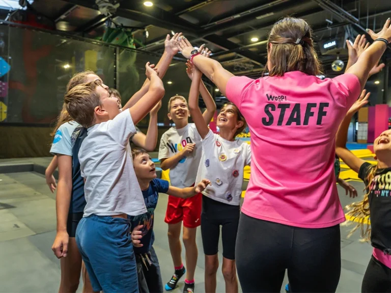 Kinder freuen sich und interagieren mit dem Staff in einer Sporthalle während einer Gruppenaktivität.