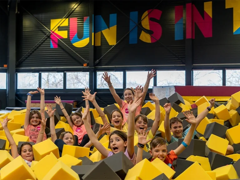 Kinder haben Spaß in einem Schaumstoffgraben, umgeben von bunten Wänden mit dem Schriftzug "FUN IS IN".