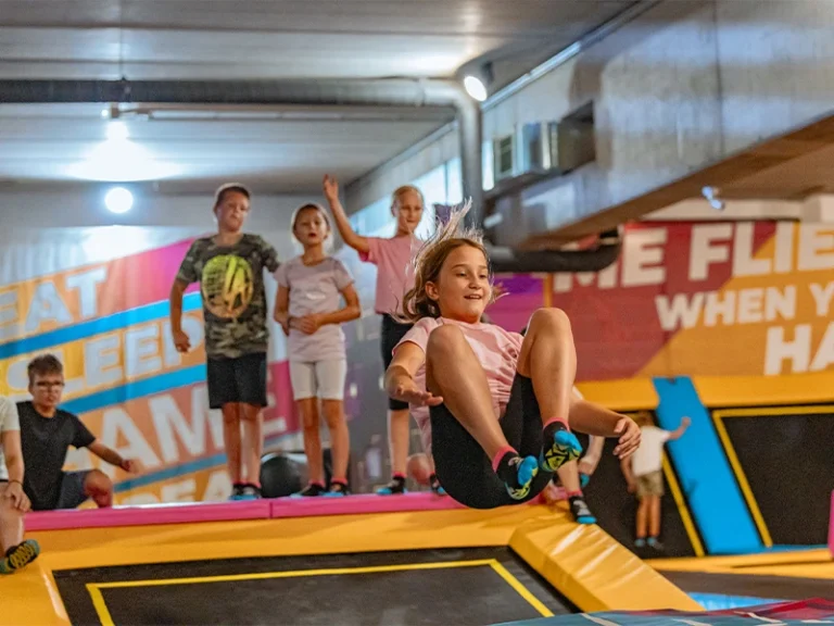 Kinder springen auf Trampolinen in einem Indoor-Spielplatz, Spaß und Bewegung stehen im Vordergrund.