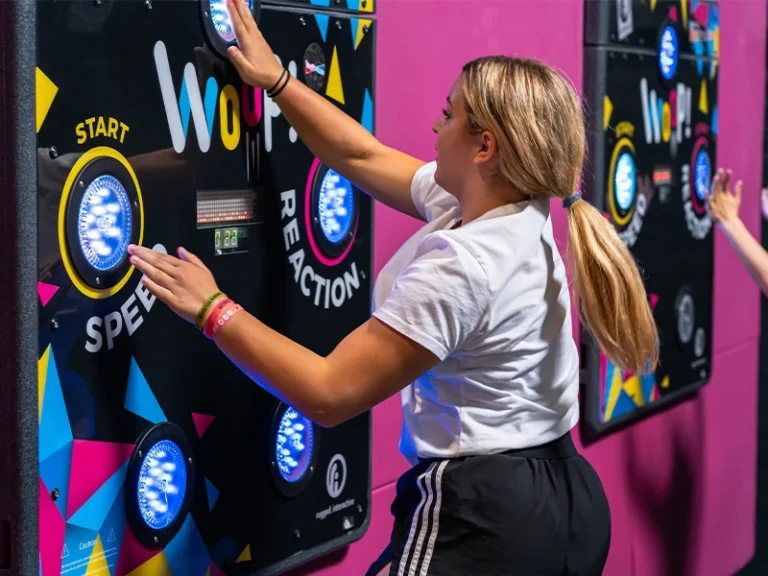 Sportlerin trainiert an interaktiven Reaktionswänden in einem modernen Fitnessstudio. Fokus auf Geschwindigkeit und Agilität.
