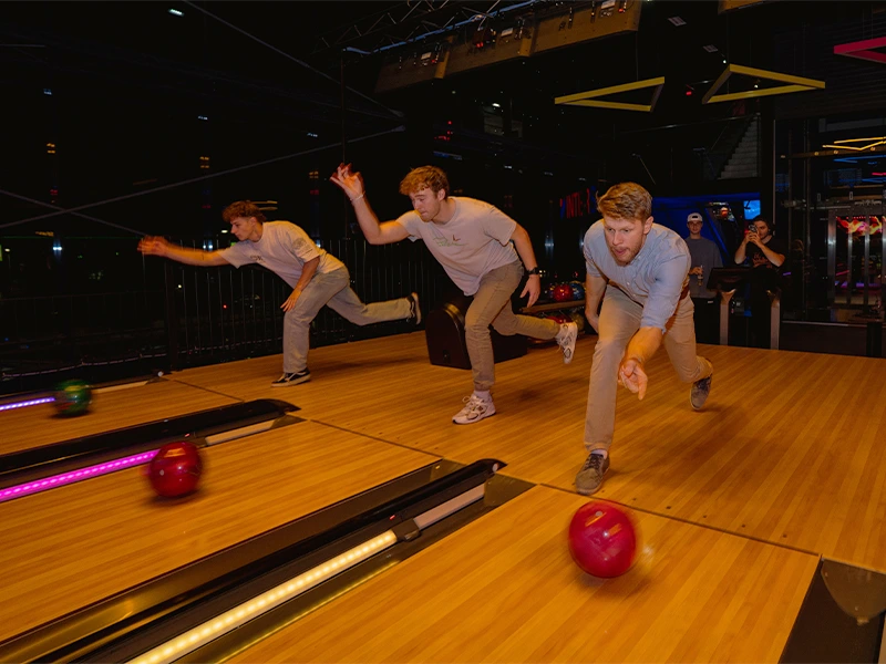 Junge Männer beim Bowling in einer modernen Bowlingbahn, konzentriert auf ihre Würfe und Spaß haben.