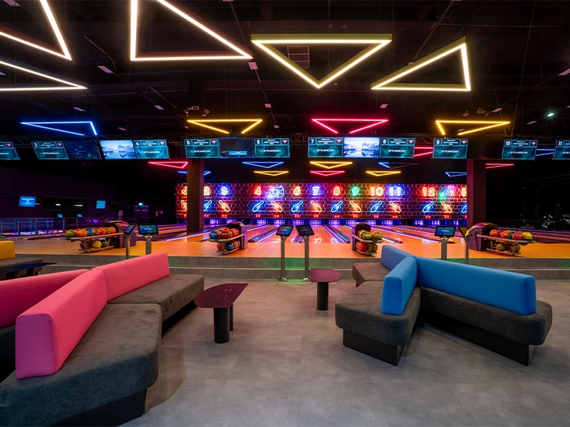 Moderne Bowlingbahn mit bunten Neonlichtern und gemütlichen Sitzbereichen für ein unterhaltsames Erlebnis.