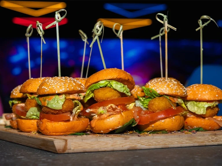 Leckere Mini-Burger auf einem Holzbrett, gefüllt mit Salat, Tomaten und knusprigen Zutaten, perfekt für Snacks.