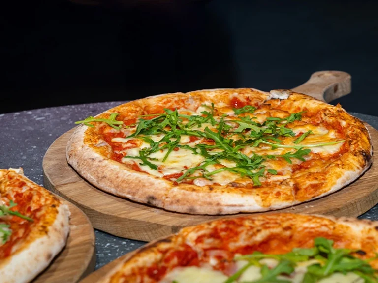 Leckere Pizza mit Tomatensauce, Käse und frischem Rucola auf Holzbrett serviert. Perfekt für jede Mahlzeit.